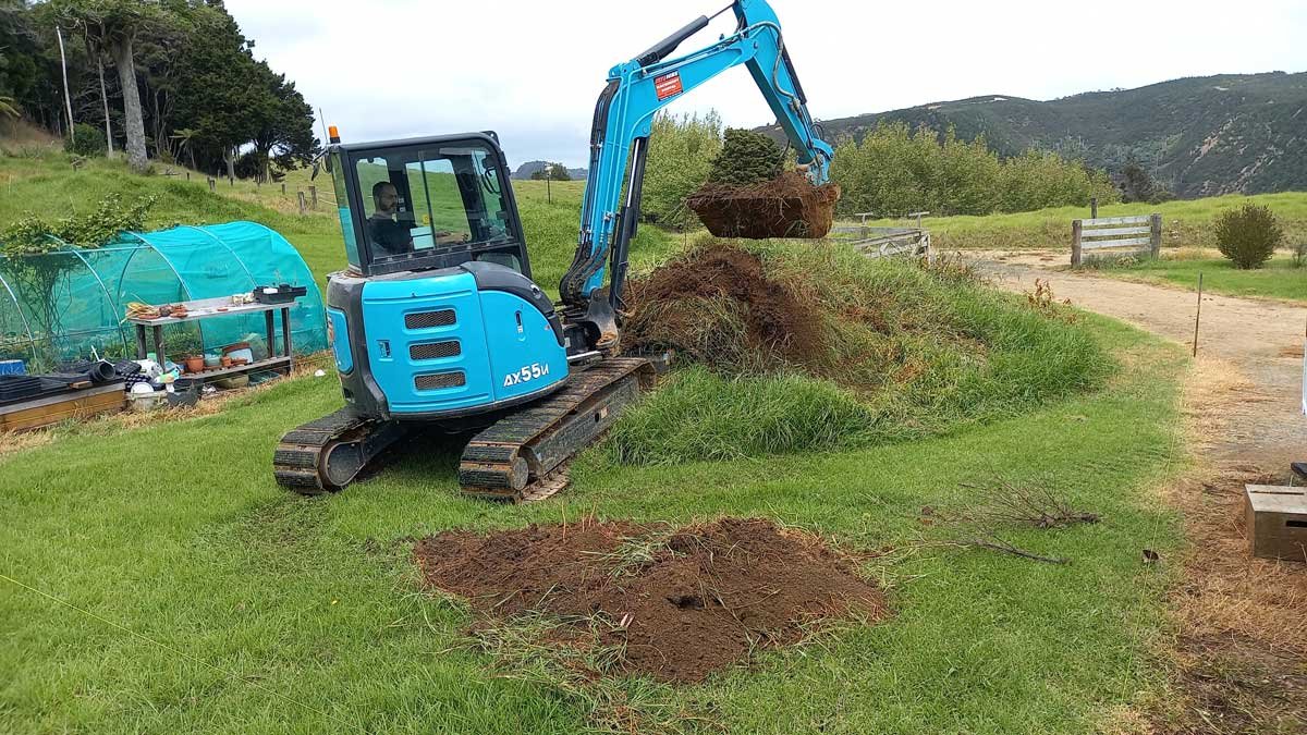 Richard begins working on the soil mound with the digger.