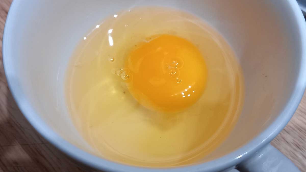 A naked egg in a white teacup.