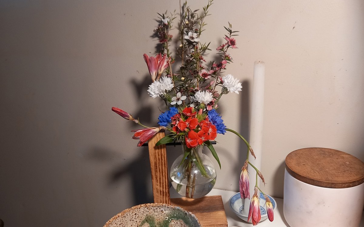 A flower arrangement featuring freesia, manuka, cornflower, and dianthus