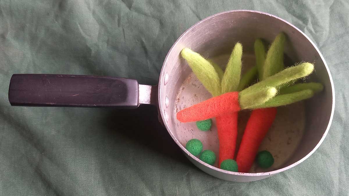 Felted peas and carrots in a toy pot.