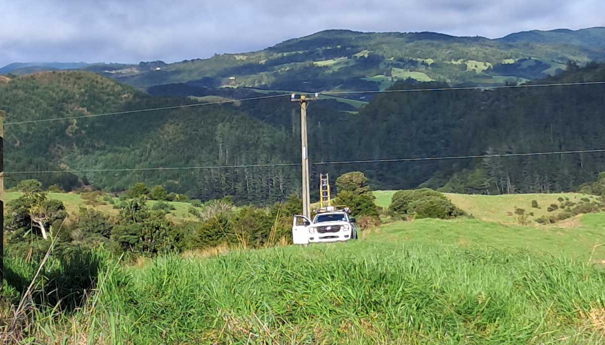 A power pylon in the middle of a paddock, with one wire swinging low. A truck sits below it as a worker lifts a ladder. A power pylon in the middle of a paddock, with one wire swinging low. A truck sits below it as a worker lifts a ladder.