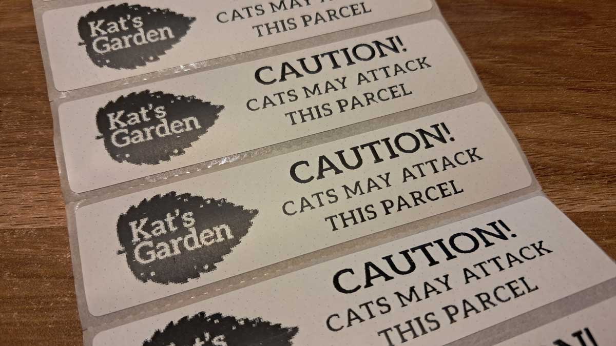 A roll of stickers with the "Kat's Garden" logo and the words 'caution: cats may attack this parcel.'