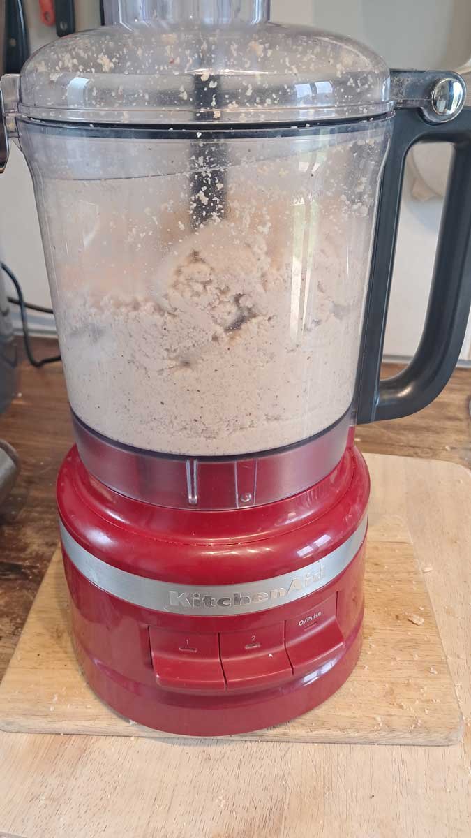 Even more crushed nuts in a blender. They are more paste-like and the volume has dropped.