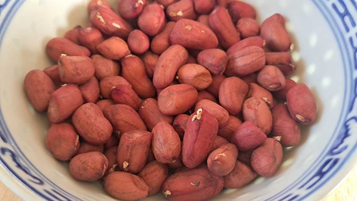 A bowl filled with raw red peanuts - peanut seed. A bowl filled with raw red peanuts - peanut seed.