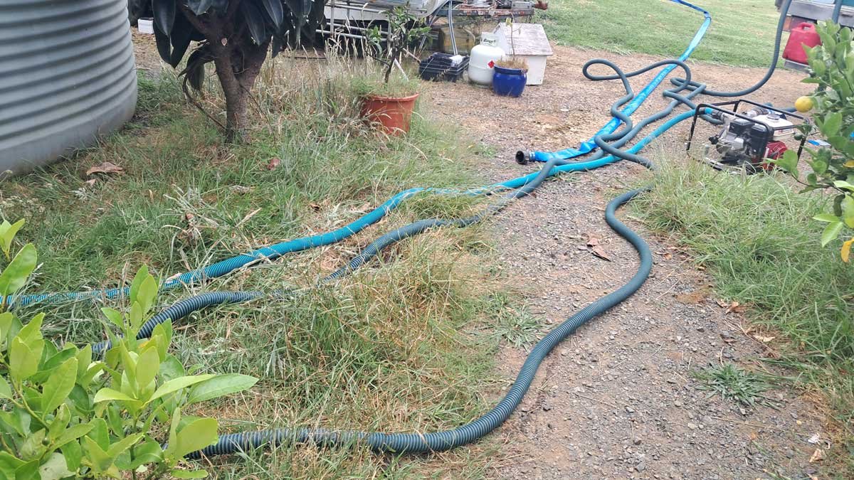Pipes and pumps laid out between the tank on the left and the truck on the right.