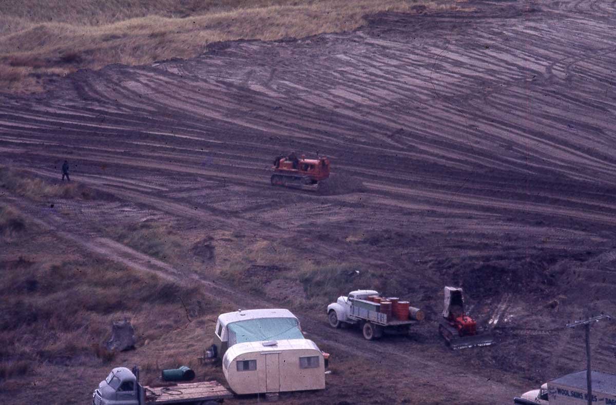 A bulldozer on the dunes at Māhia, around 1963. In the foreground is the caravan the family slept in on weekends.