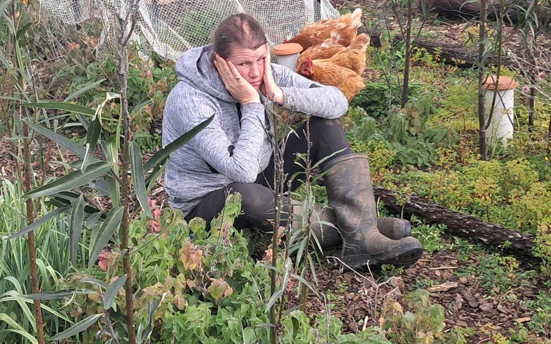 Kat looking overwhelmed in a part of the garden overrun by weeds.