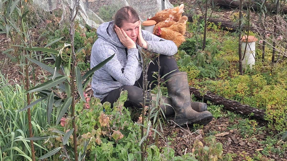 Kat looking overwhelmed in a part of the garden overrun by weeds.
