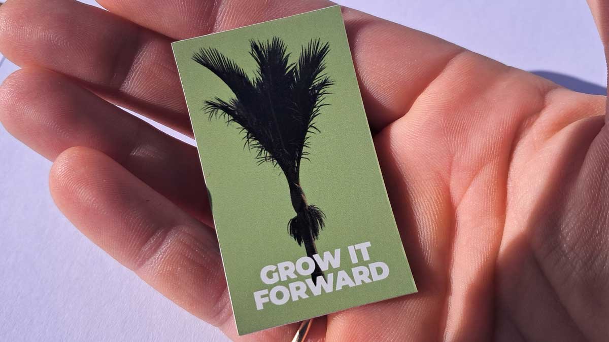 A "grow it forward" sticker in a hand. A "grow it forward" sticker in a hand.