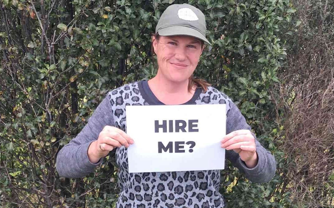 Kat Jenkins holding a sign saying "hire me?"